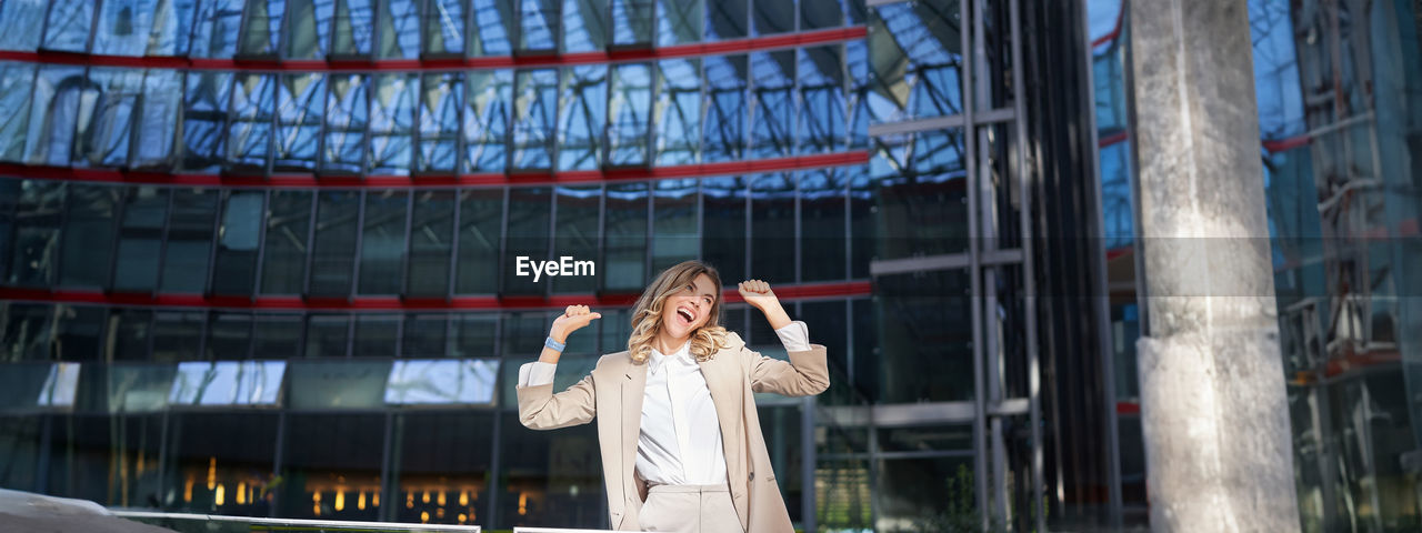 portrait of young woman standing against built structures