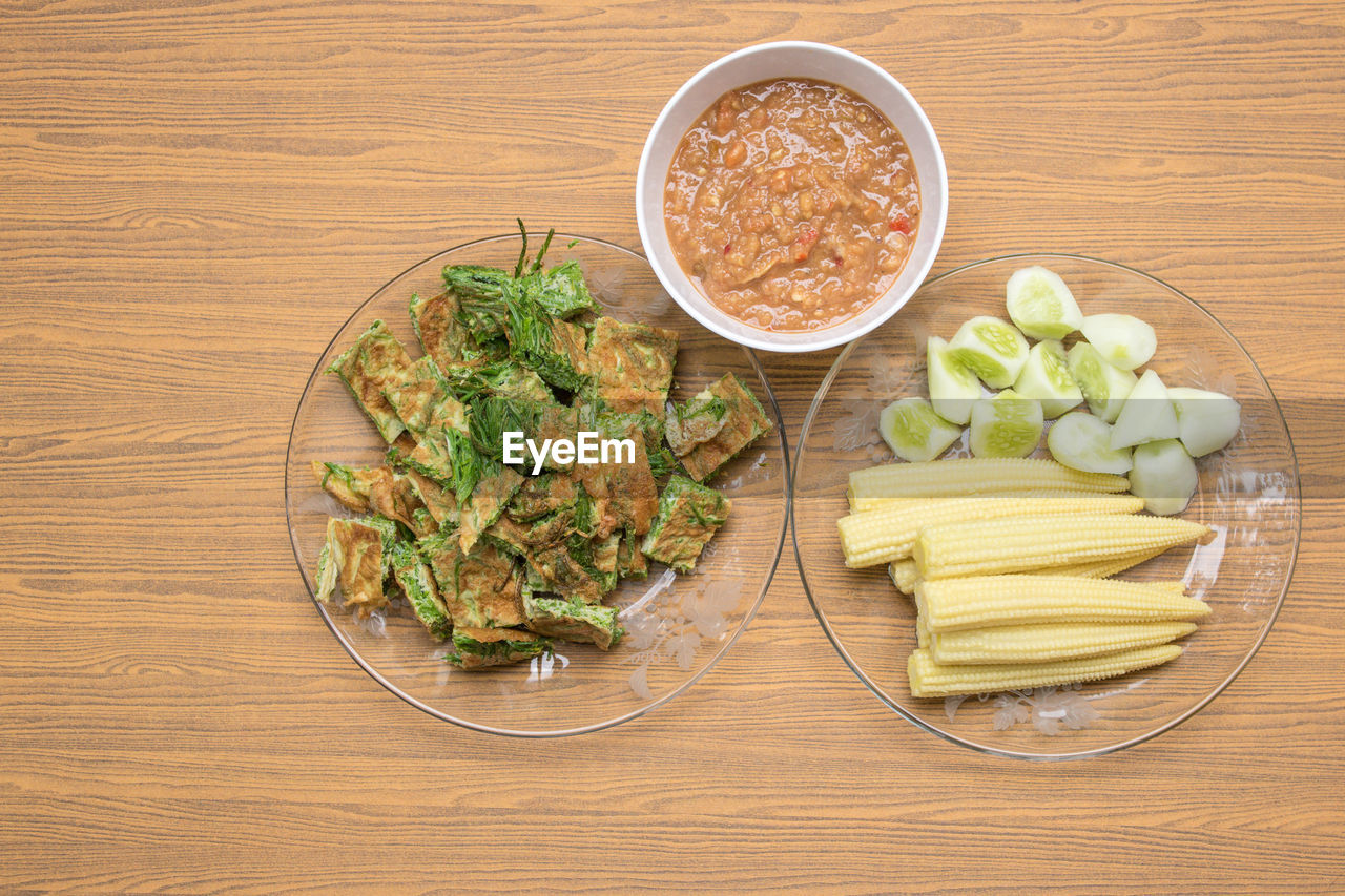 High angle view of food in plates and bowl on wooden table