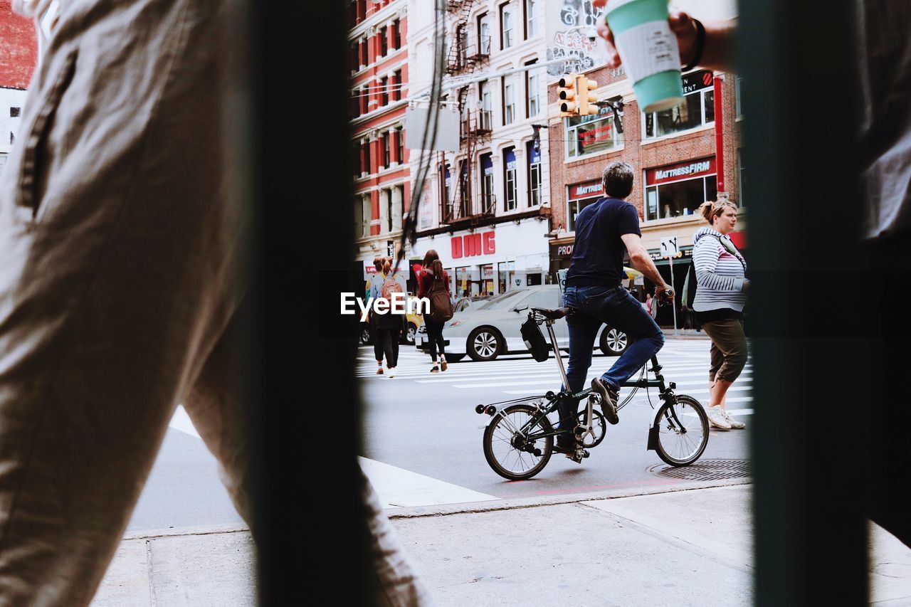 PEOPLE RIDING BICYCLE ON STREET AGAINST BUILDINGS