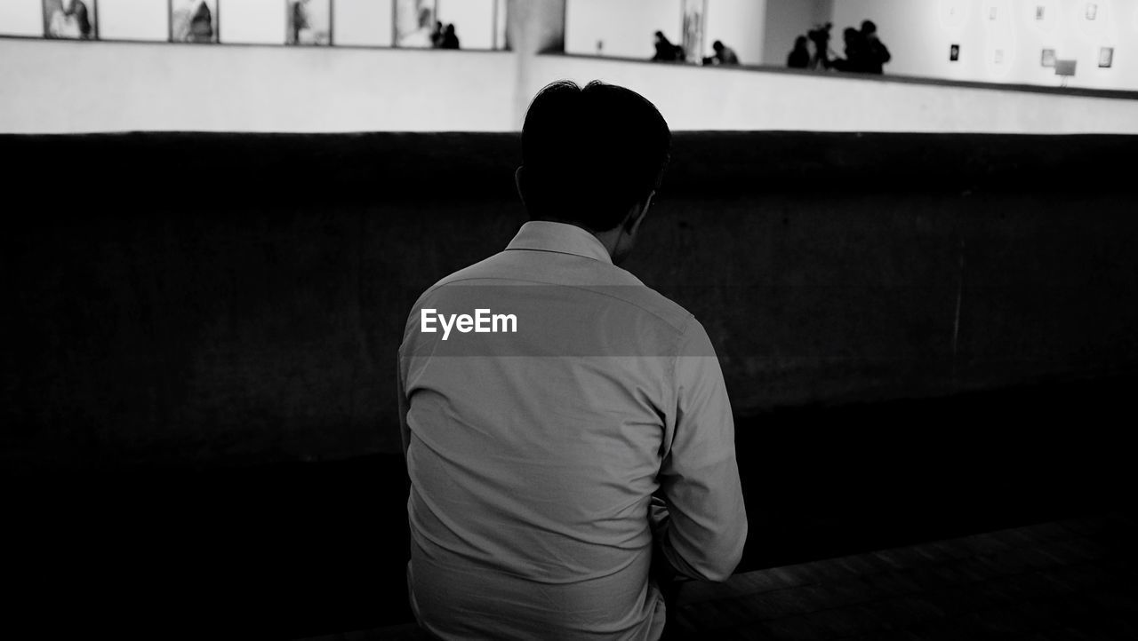 Rear view of man sitting on bench at night