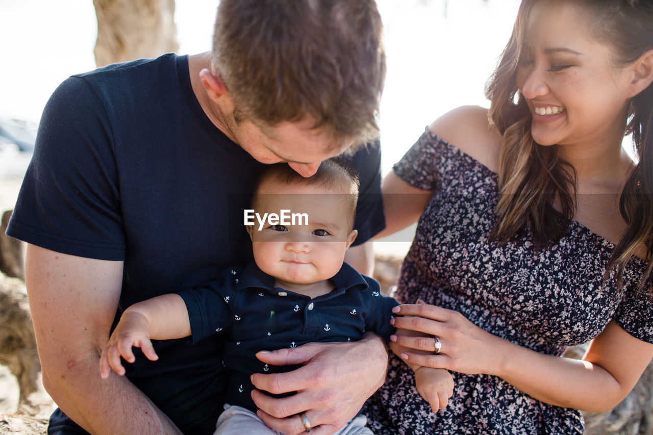 Dad kissing son on head while mom smiles