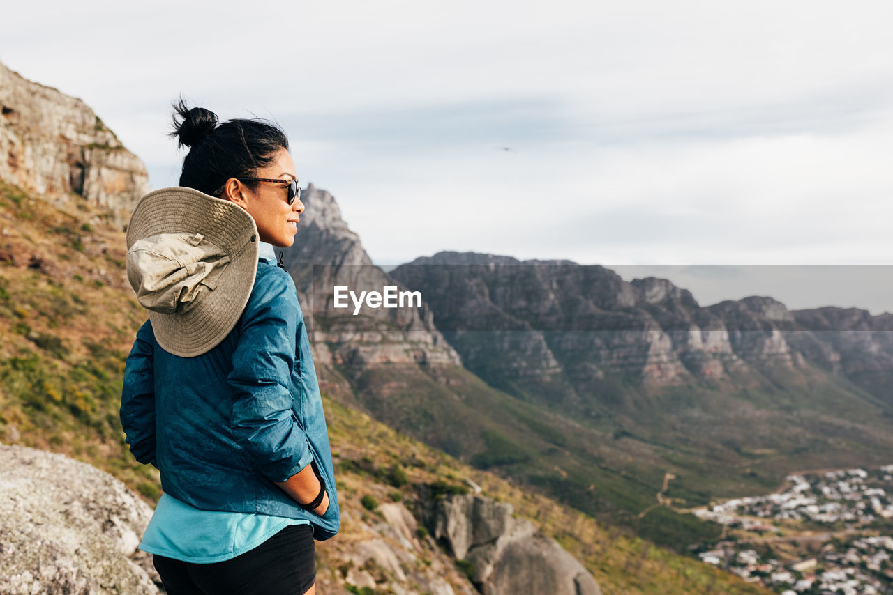 side view of man photographing on mountain against sky