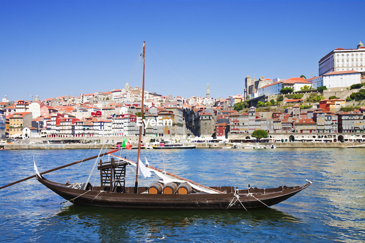 Boats in canal by buildings against clear blue sky