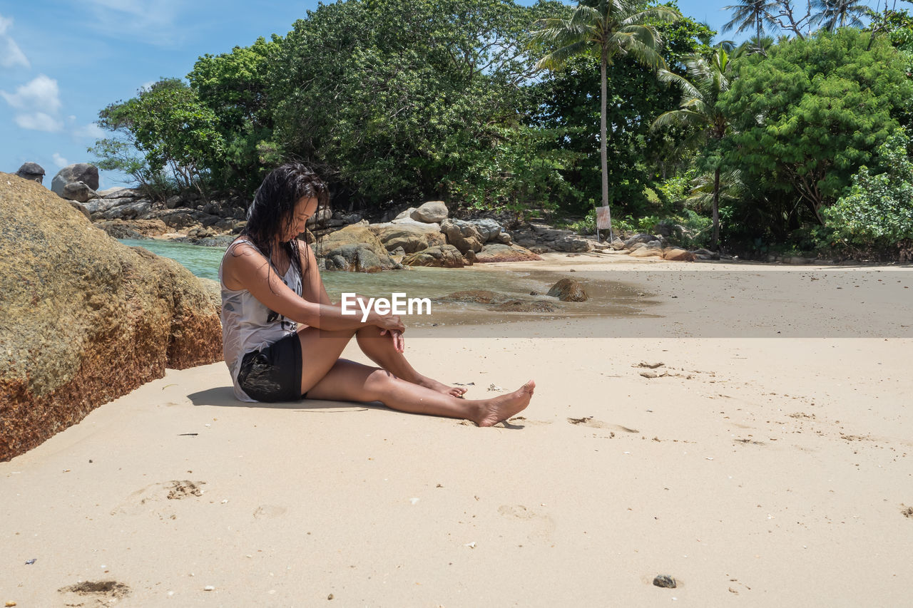 Side view of woman sitting on beach