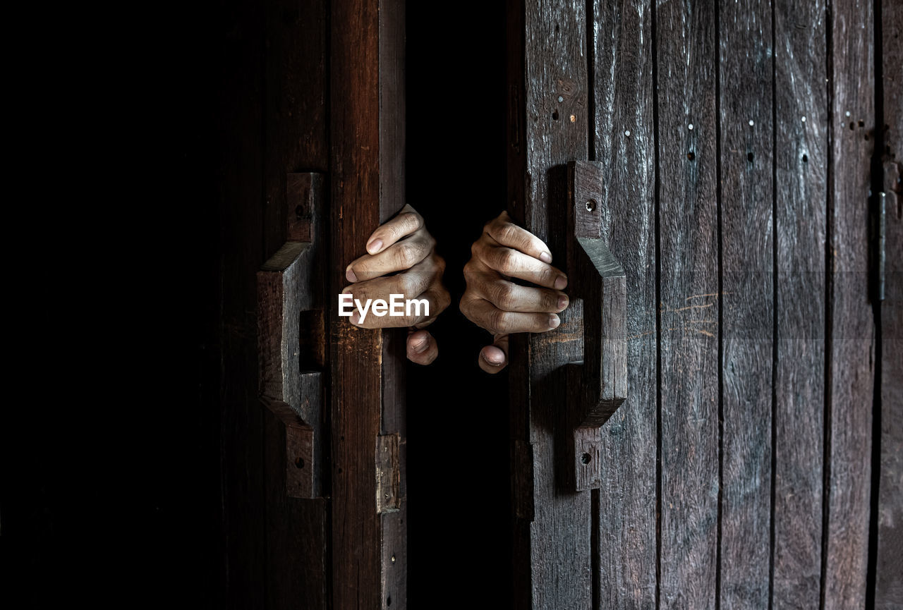 CLOSE-UP OF HAND ON DOOR OF METAL STRUCTURE