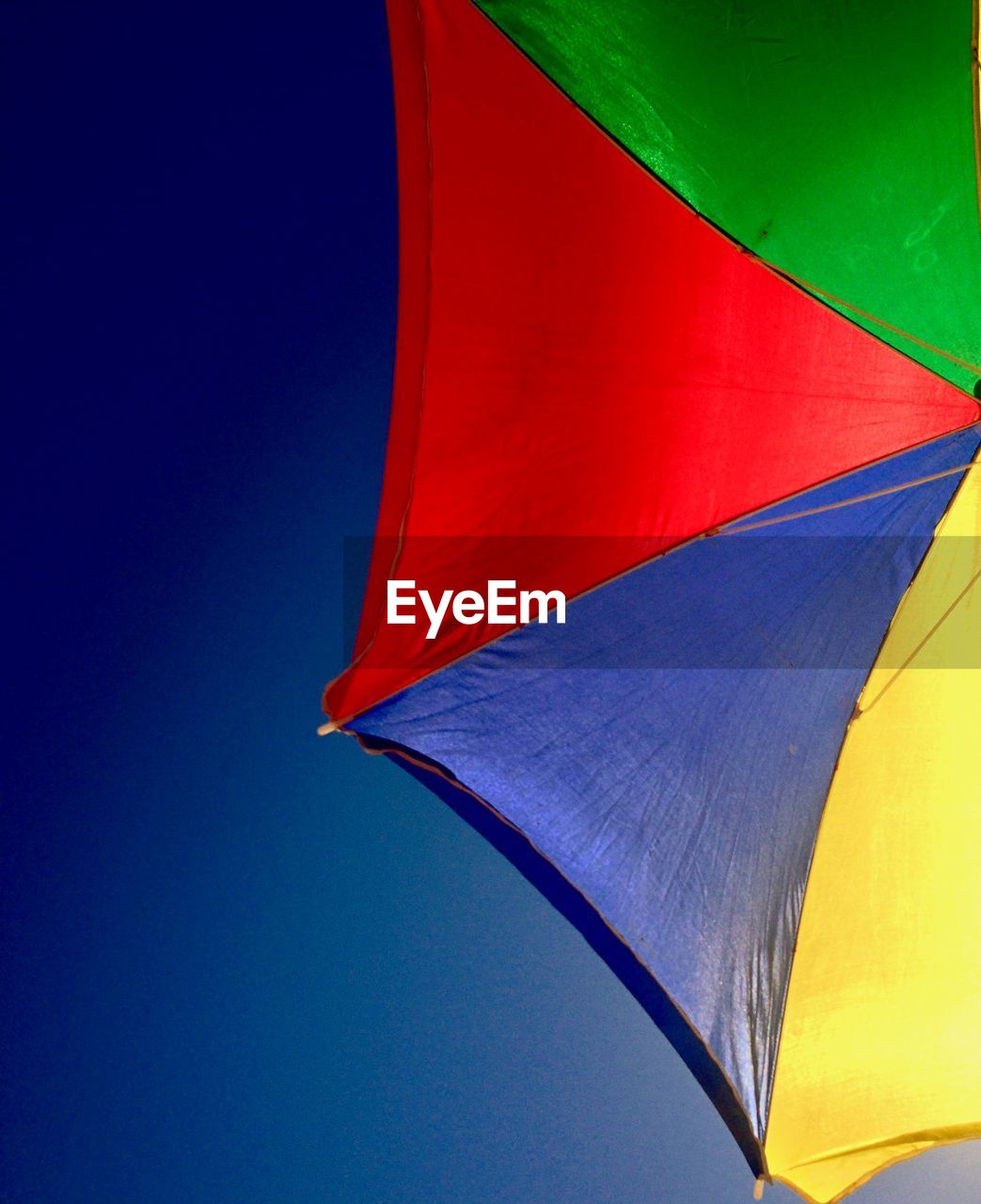 Low angle view of parasol against clear blue sky