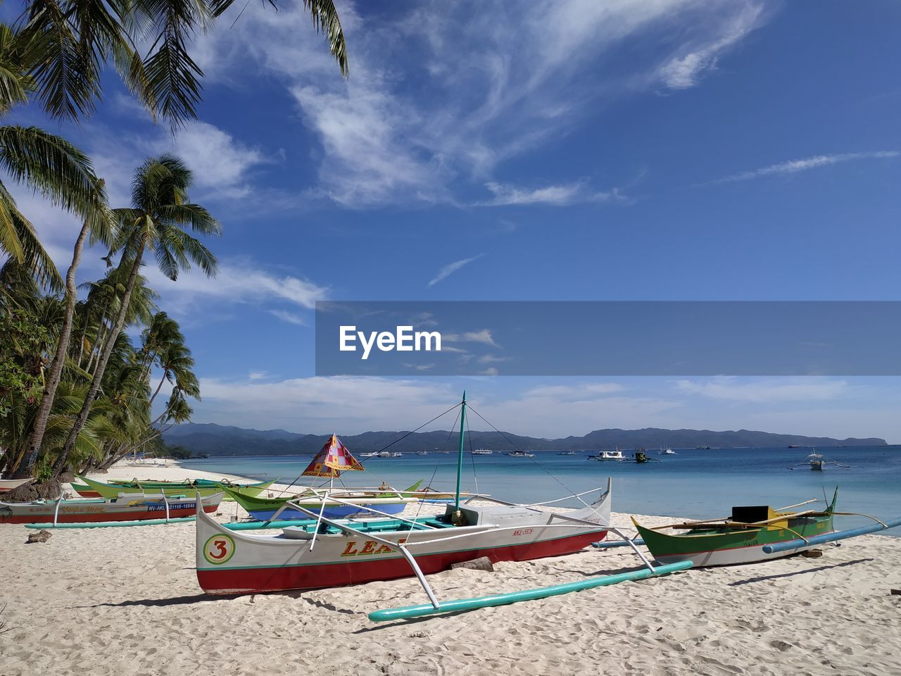 BOATS MOORED ON BEACH AGAINST SKY