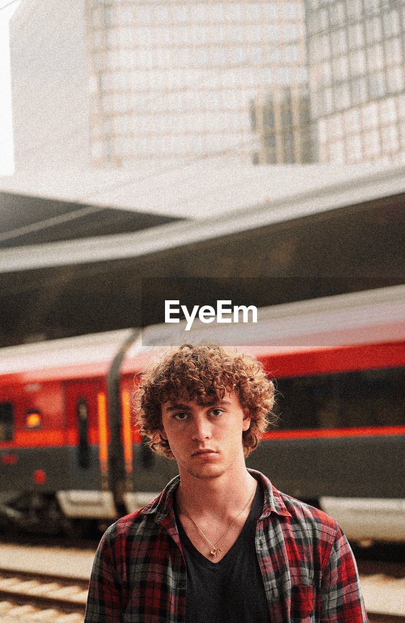 Portrait of young man standing against train