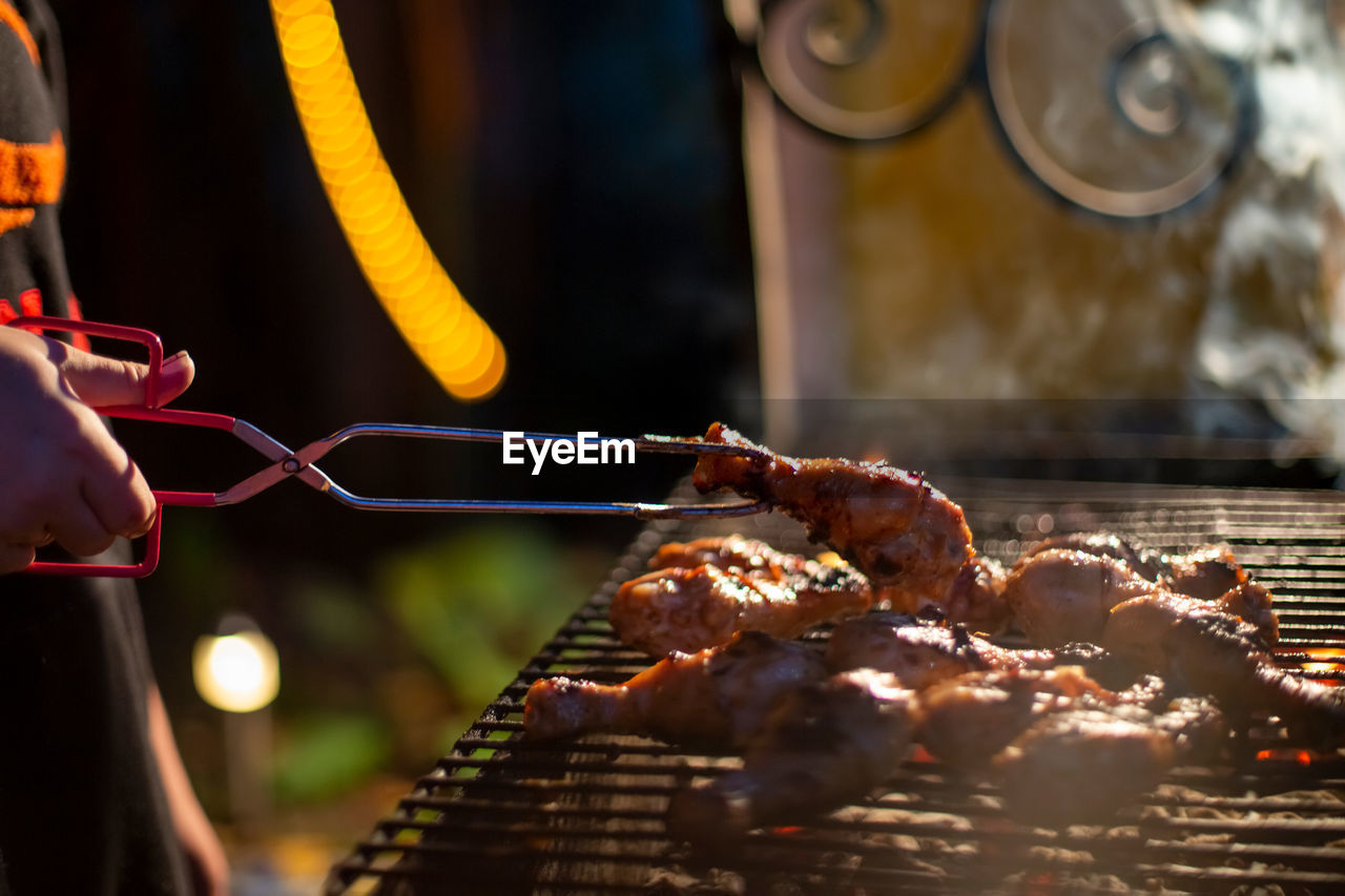 PERSON HOLDING MEAT ON BARBECUE