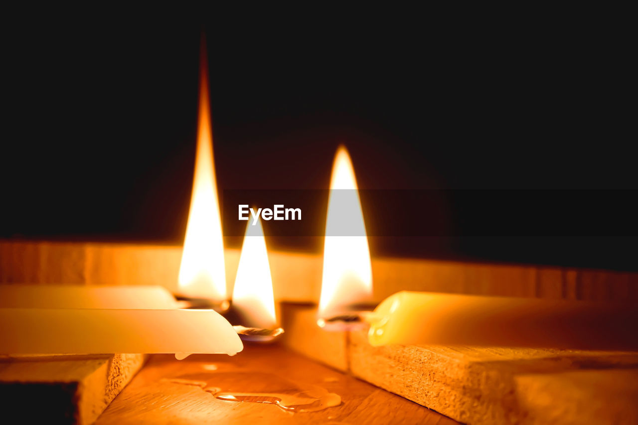 White candles burning in the dark with lights glow, the burning candle's flame in the dark