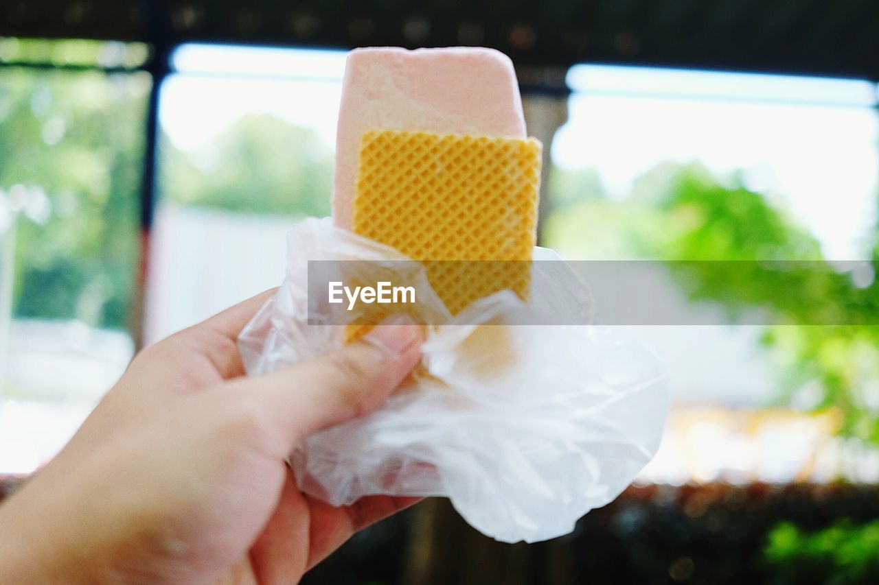 CLOSE-UP OF HAND HOLDING ICE CREAM IN GLASS