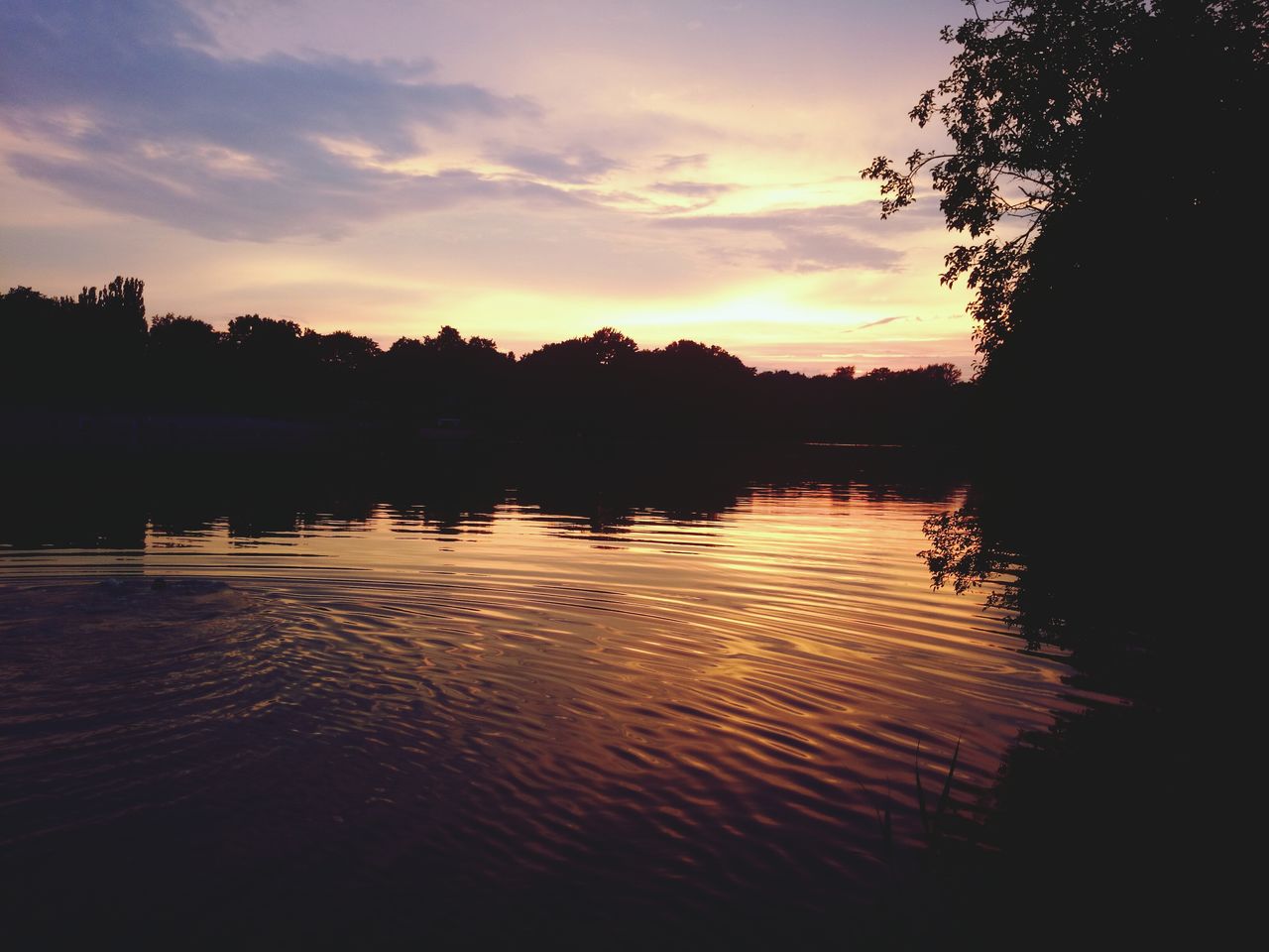 Scenic view of lake by silhouette trees against sky