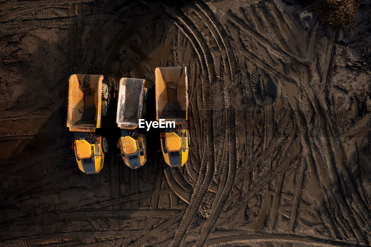 Aerial view above dumper truck or earth mover vehicle with muddy soil on construction site