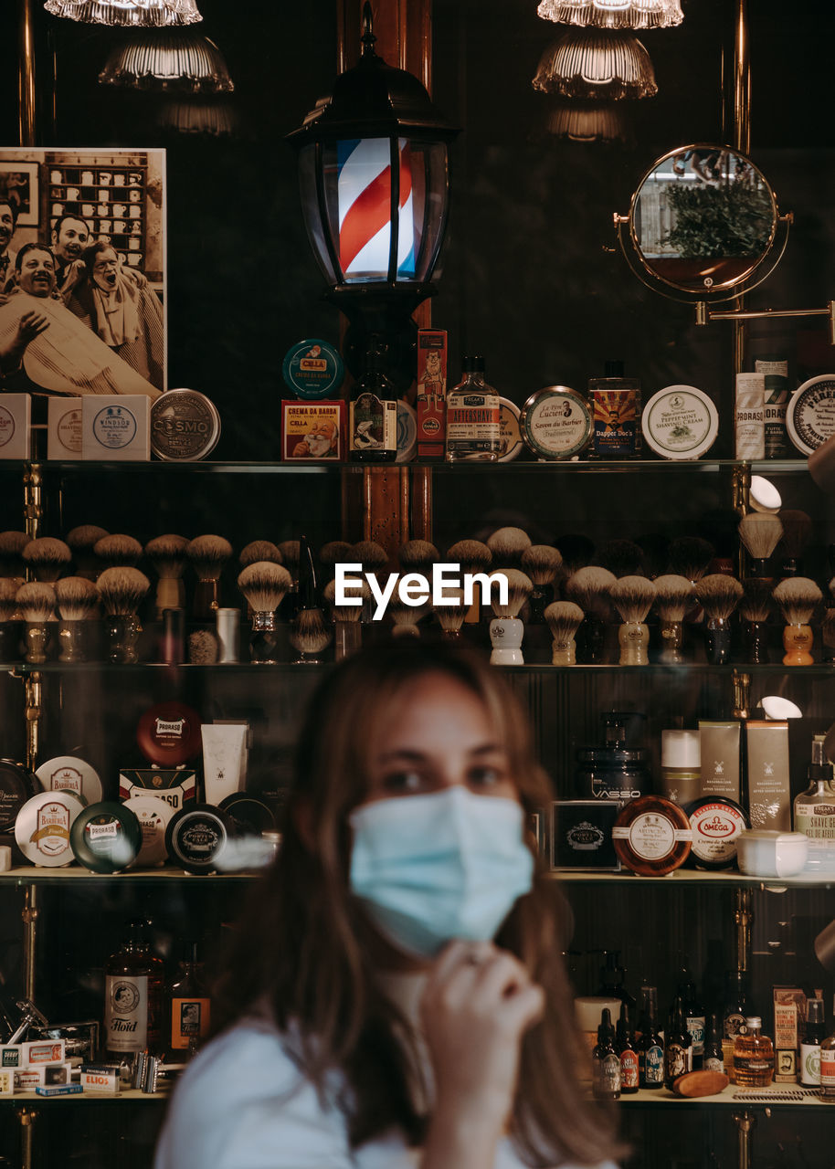 Portrait of woman standing in front of barbershop window with focus on the background