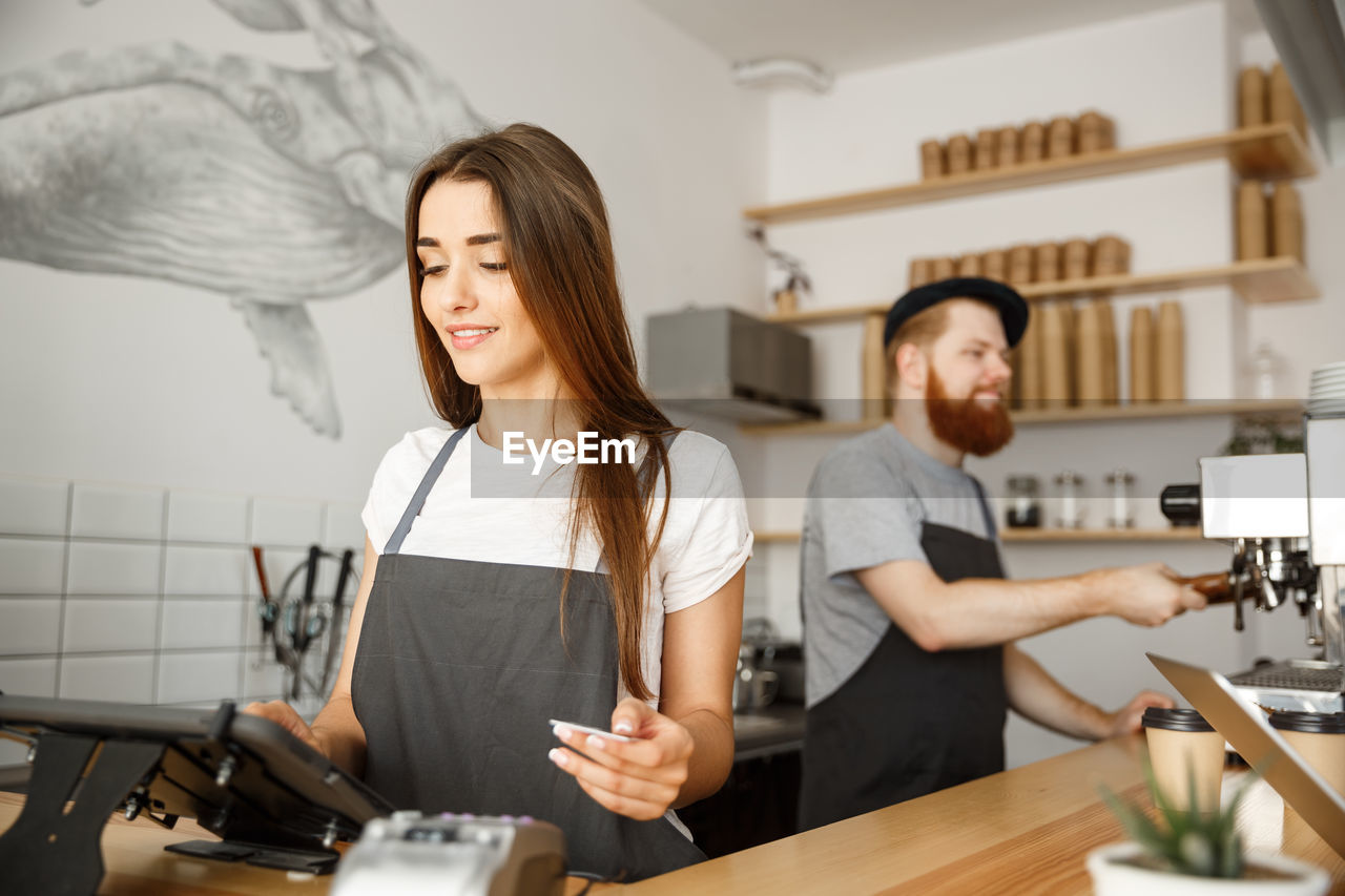 portrait of young woman using mobile phone while sitting at table