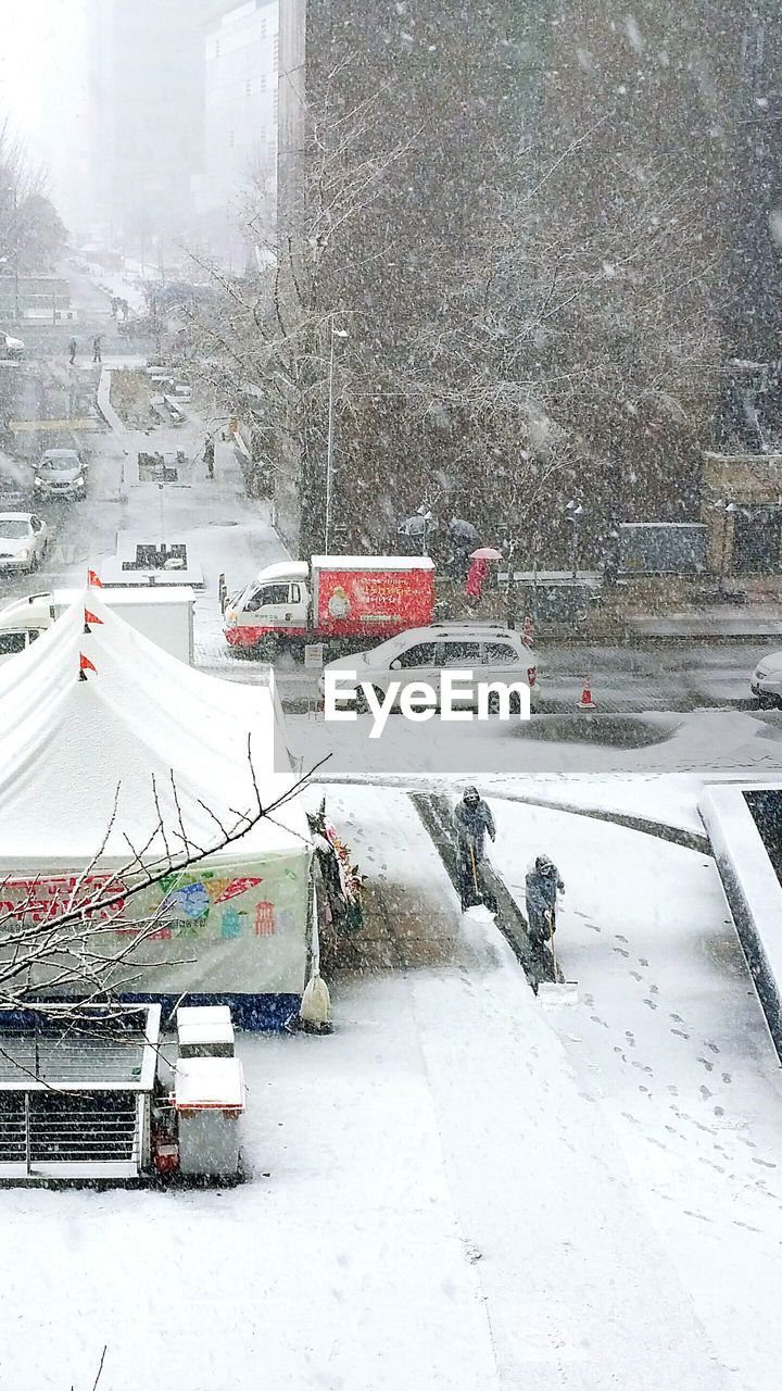 High angle view of road by buildings in city during snowfall