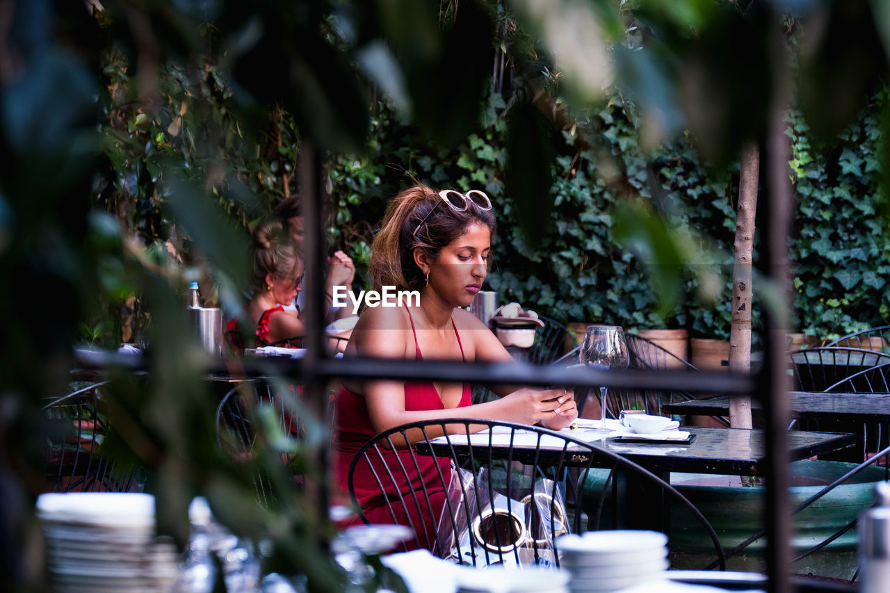 PORTRAIT OF YOUNG WOMAN SITTING ON TABLE AT PARK