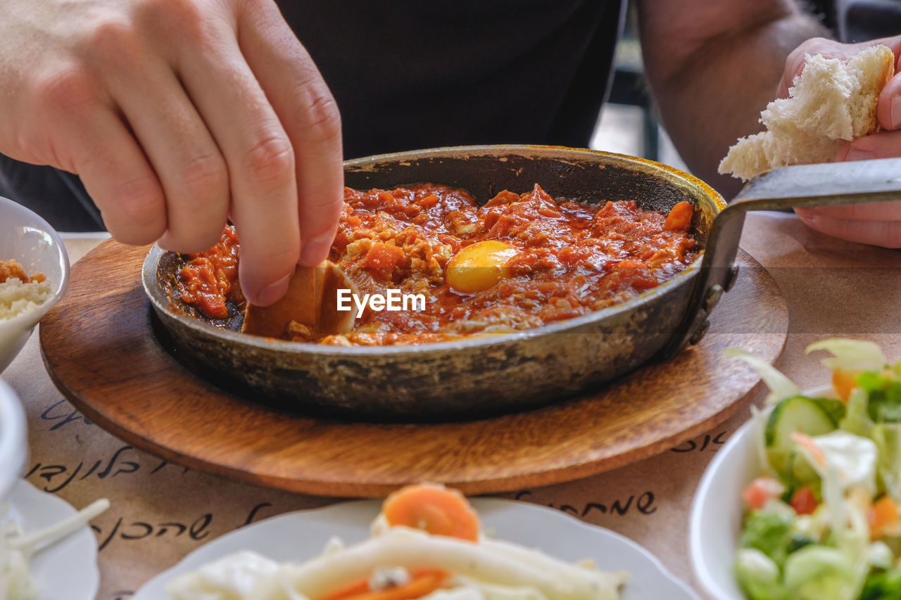 Close-up of person eating shakshouka on table