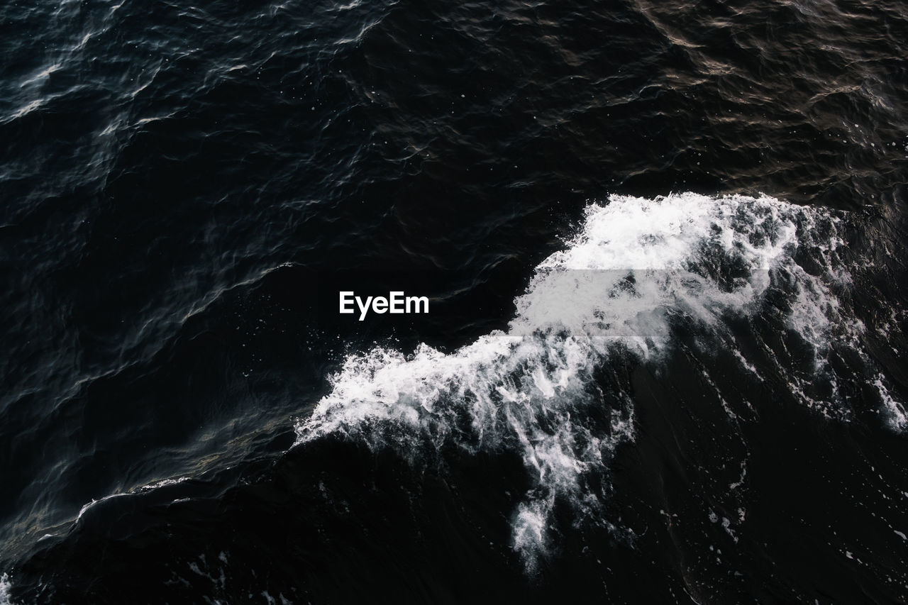 High angle view of dark sea with white foam