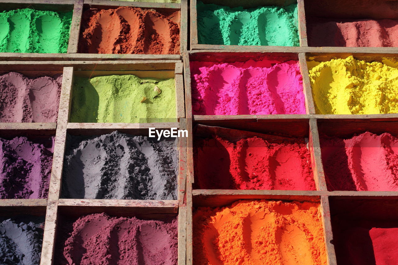 Full frame shot of colorful powder paints in wooden containers at market stall