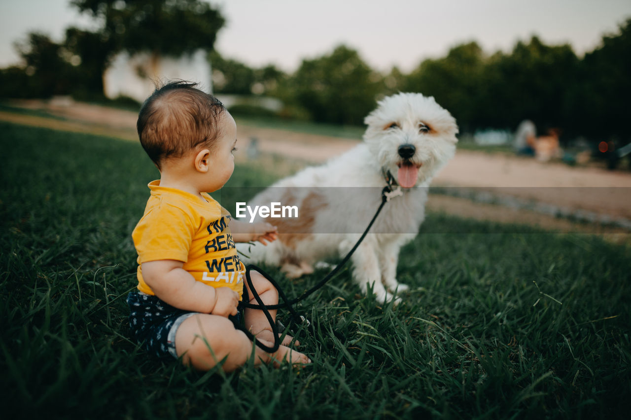 Full length of a child and dog on field