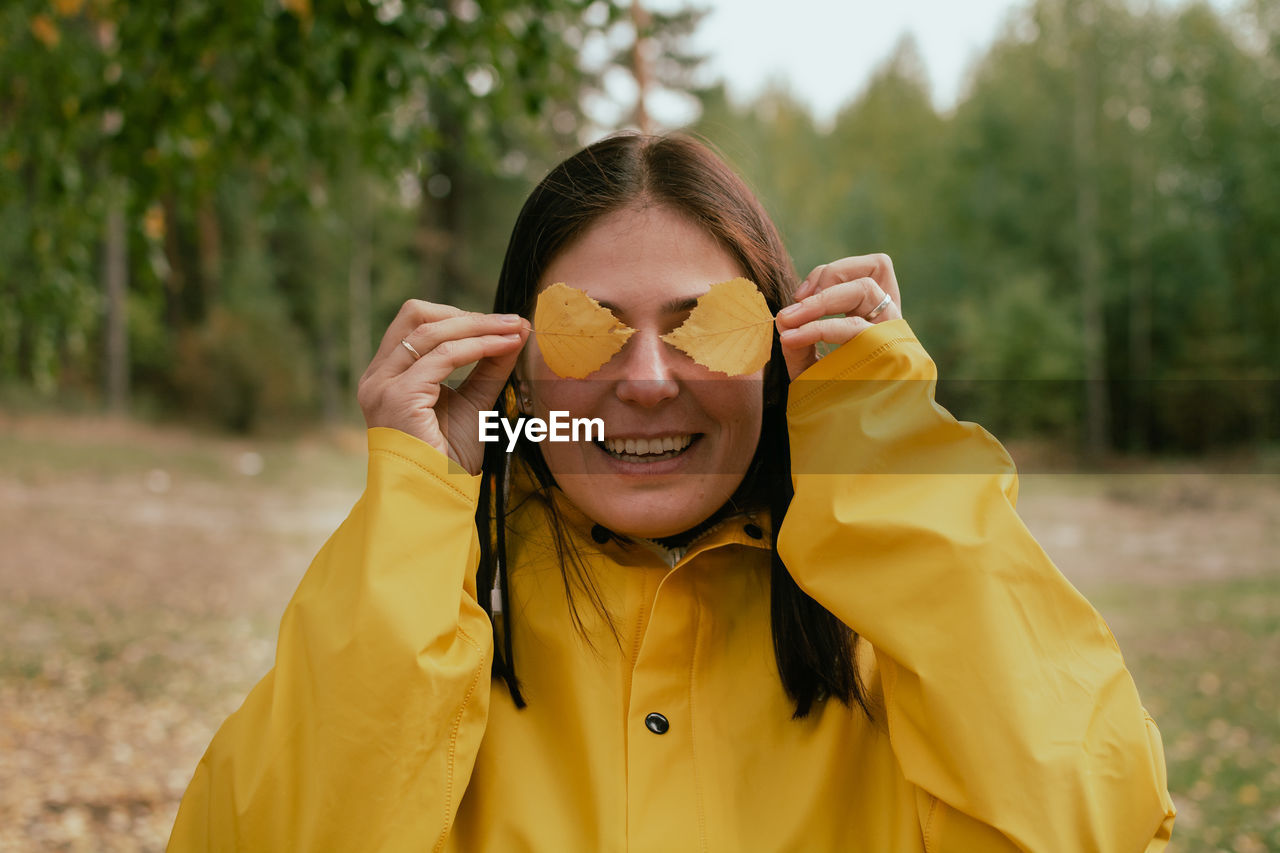 Cheerful young woman in a yellow raincoat and yellow boots poses for the camera. person