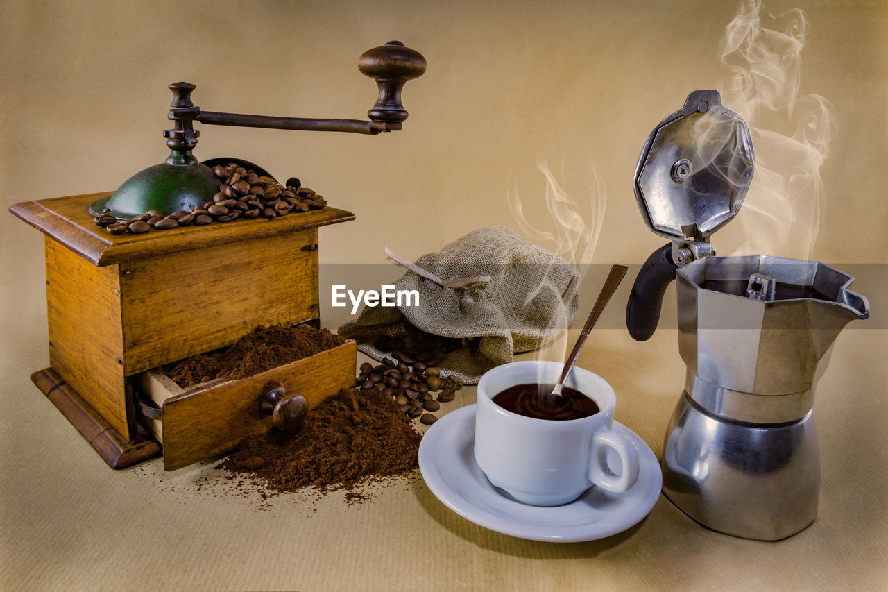 High angle view of coffee maker with beans on beige background