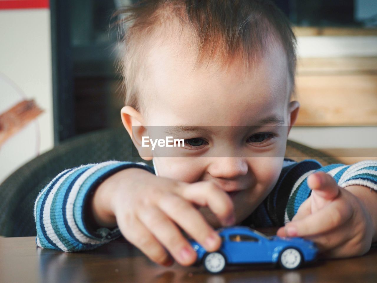 Cute boy playing with toy car at home