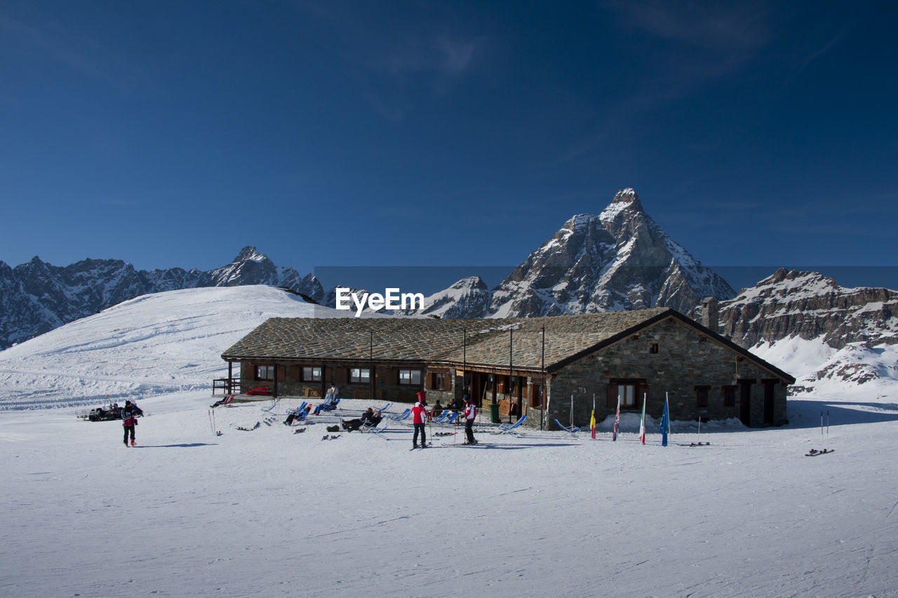 PEOPLE WALKING ON SNOWCAPPED MOUNTAIN AGAINST SKY