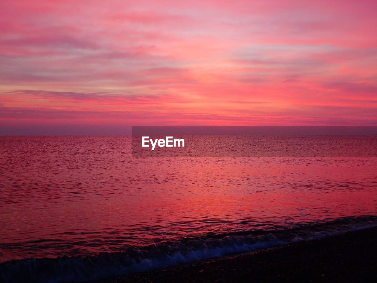 Scenic view of sea against dramatic sky during sunset