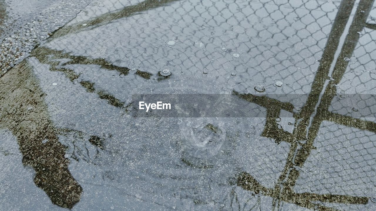 Reflection of chainlink fence in puddle during rainy season