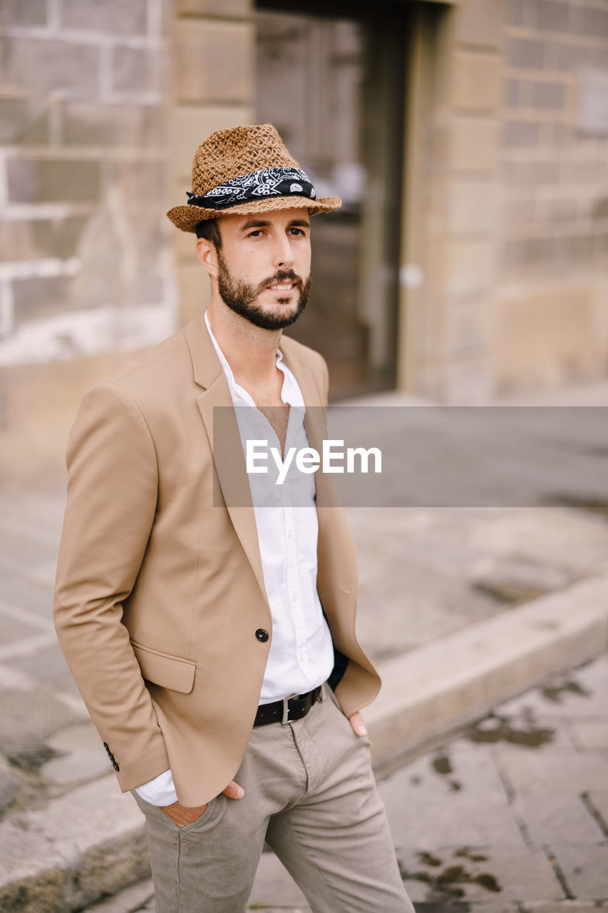 Man wearing hat looking away while standing outdoors