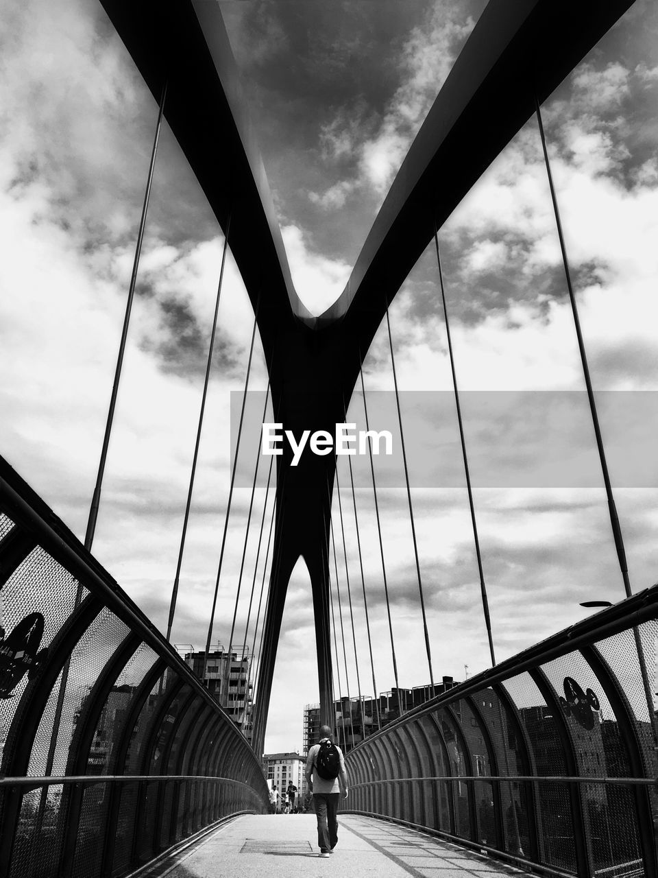 Low angle view of suspension bridge against cloudy sky