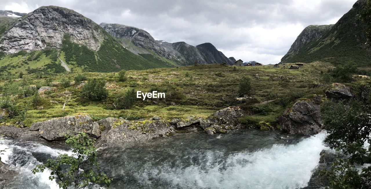 Scenic view of river flowing through rocks against sky