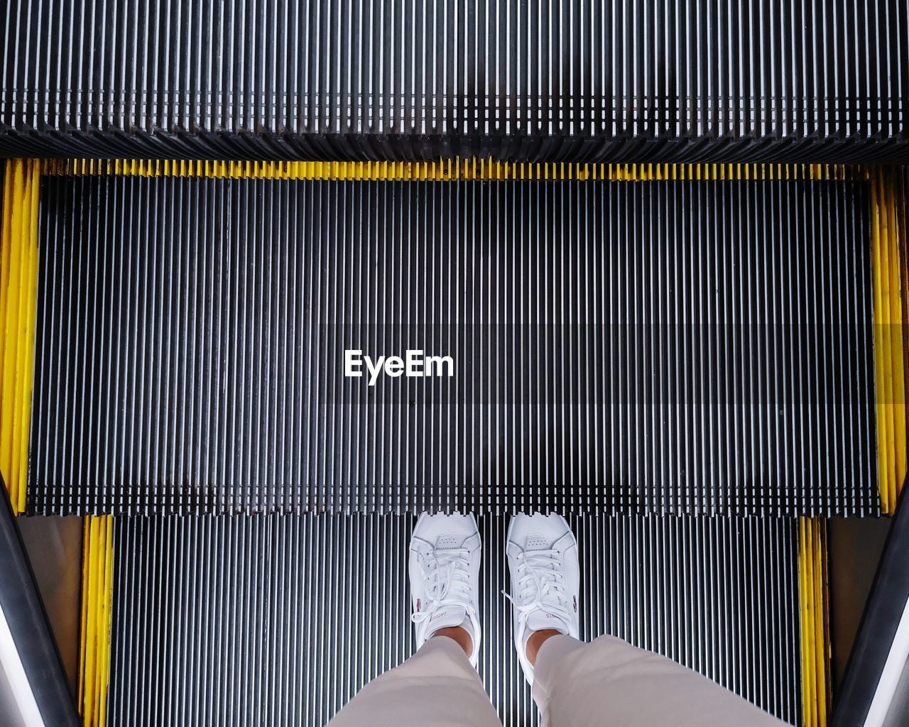 Low section of man standing on escalator