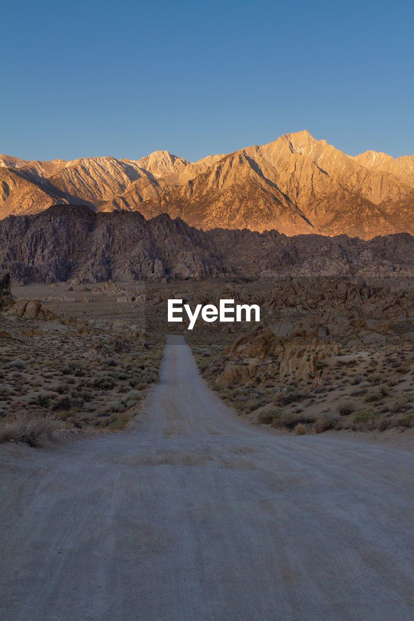 Movie road in alabama hills leading into the sierra nevadas lit by brilliant morning sun