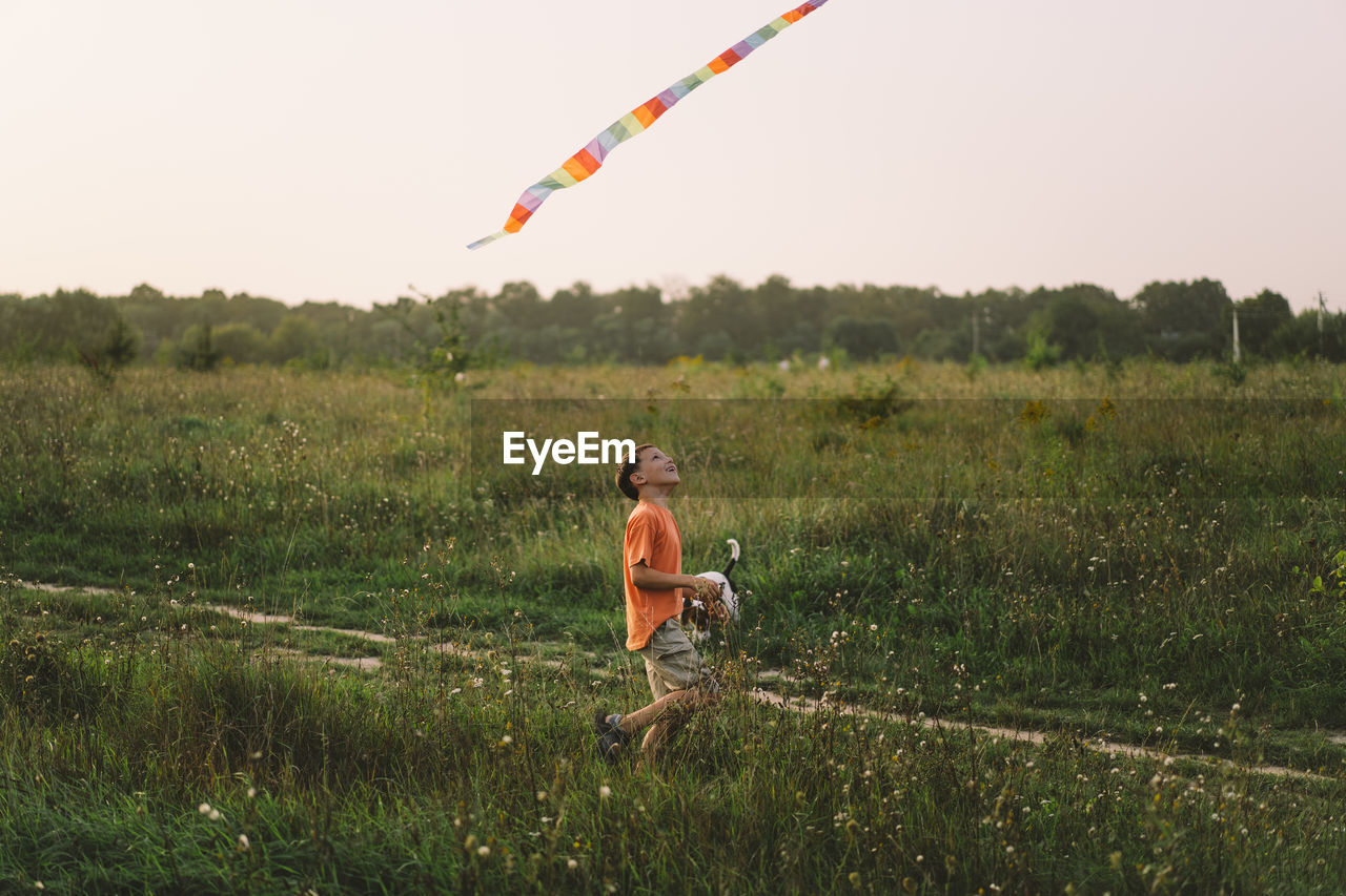 Happy family and children run on meadow with a kite in the summer on the nature.