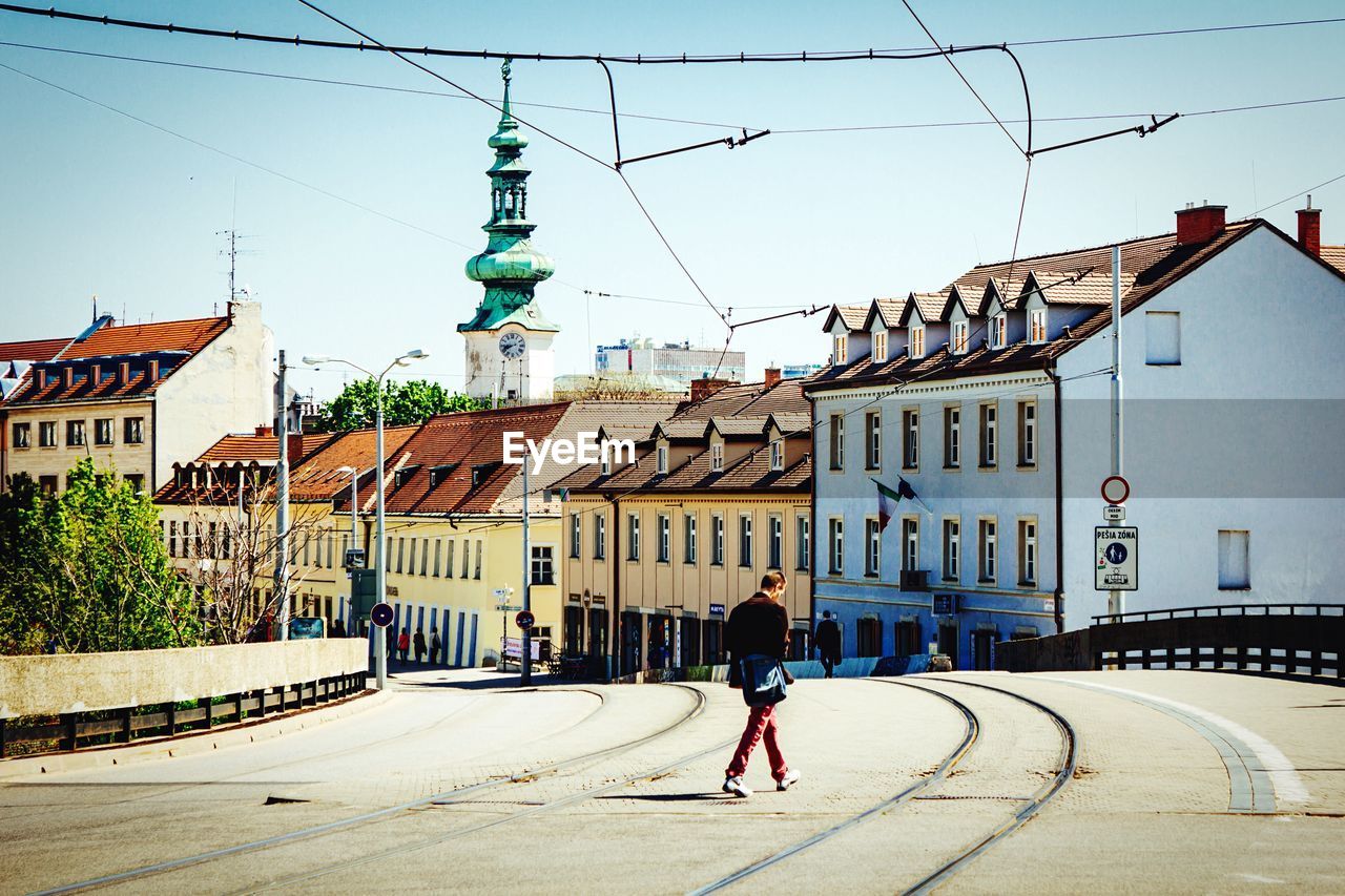 Man crossing street with railroad tracks