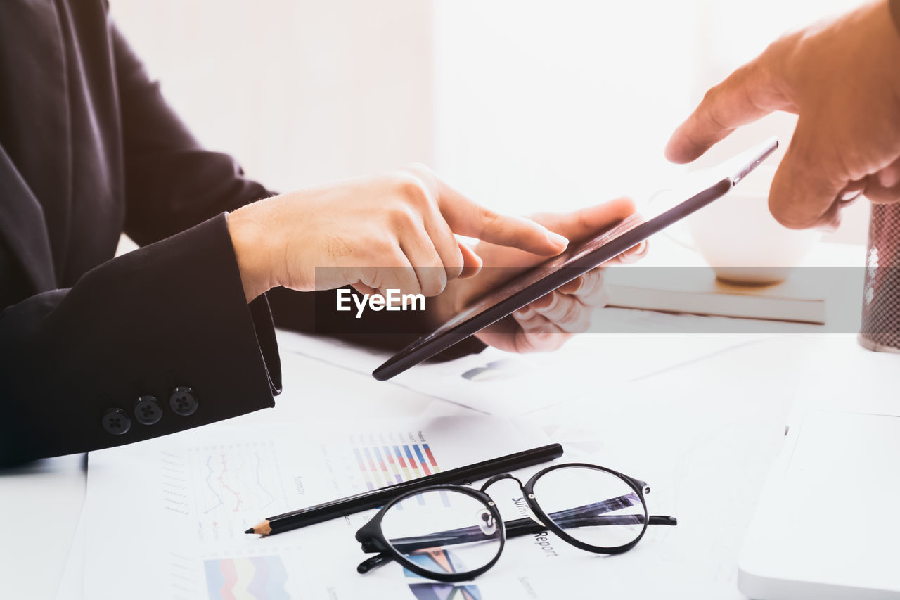 Cropped image of business people discussing over digital tablet in office