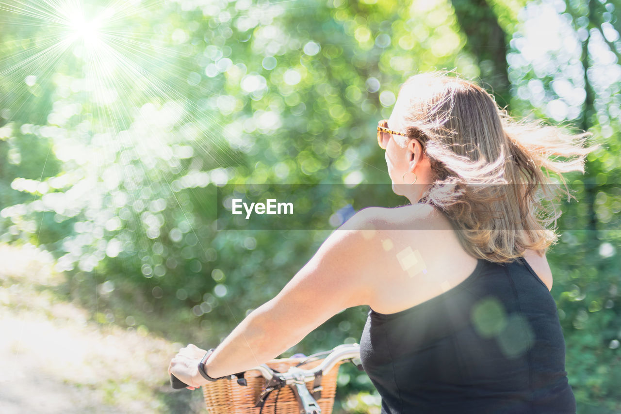 Rear view of woman riding bicycle against trees