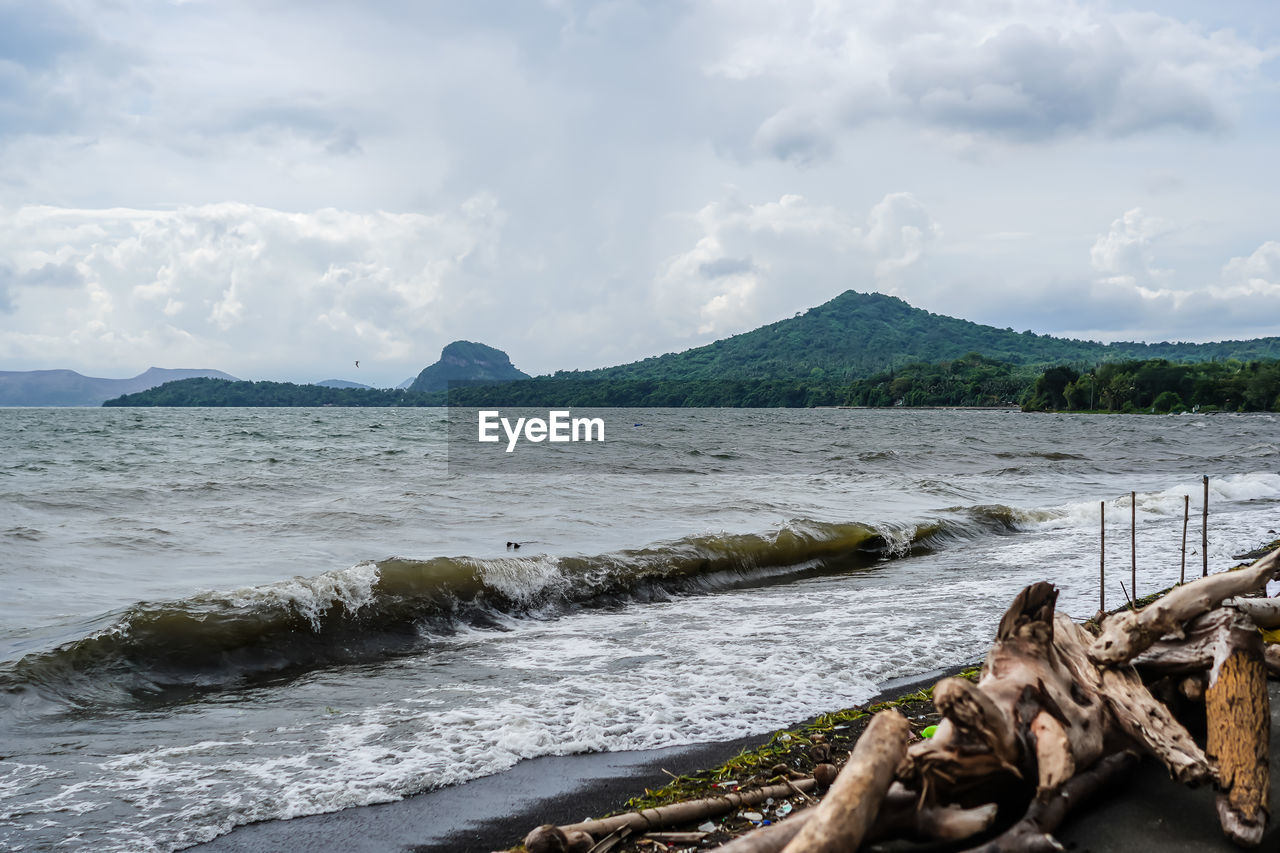 water, shore, sea, sky, coast, land, cloud, body of water, scenics - nature, nature, ocean, beach, beauty in nature, mountain, rock, environment, no people, tranquility, wave, day, tranquil scene, landscape, bay, travel destinations, outdoors, travel, non-urban scene, coastline, tree, idyllic, vacation, wood, cove, tourism