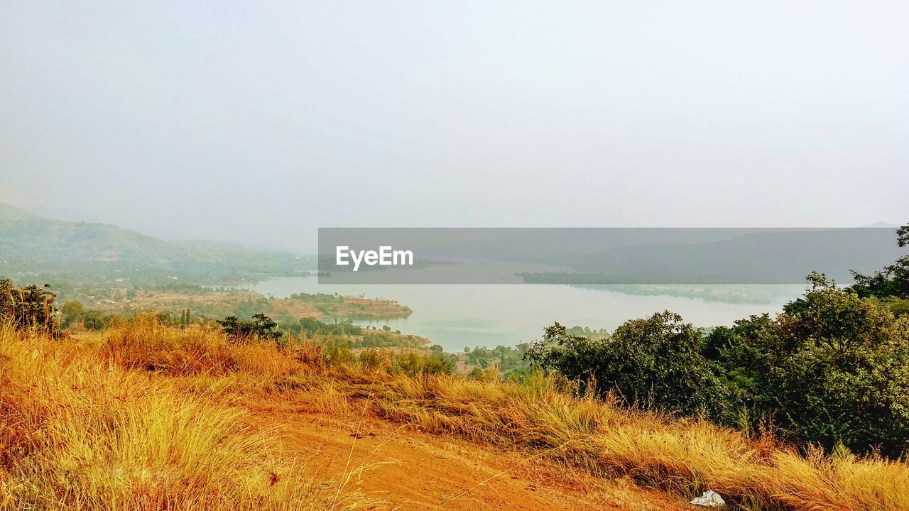 SCENIC VIEW OF FIELD BY MOUNTAINS AGAINST CLEAR SKY