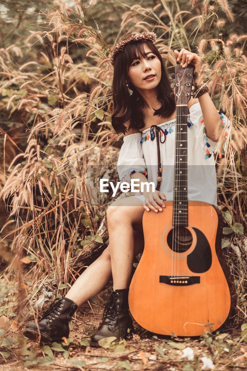 WOMAN PLAYING GUITAR ON FIELD