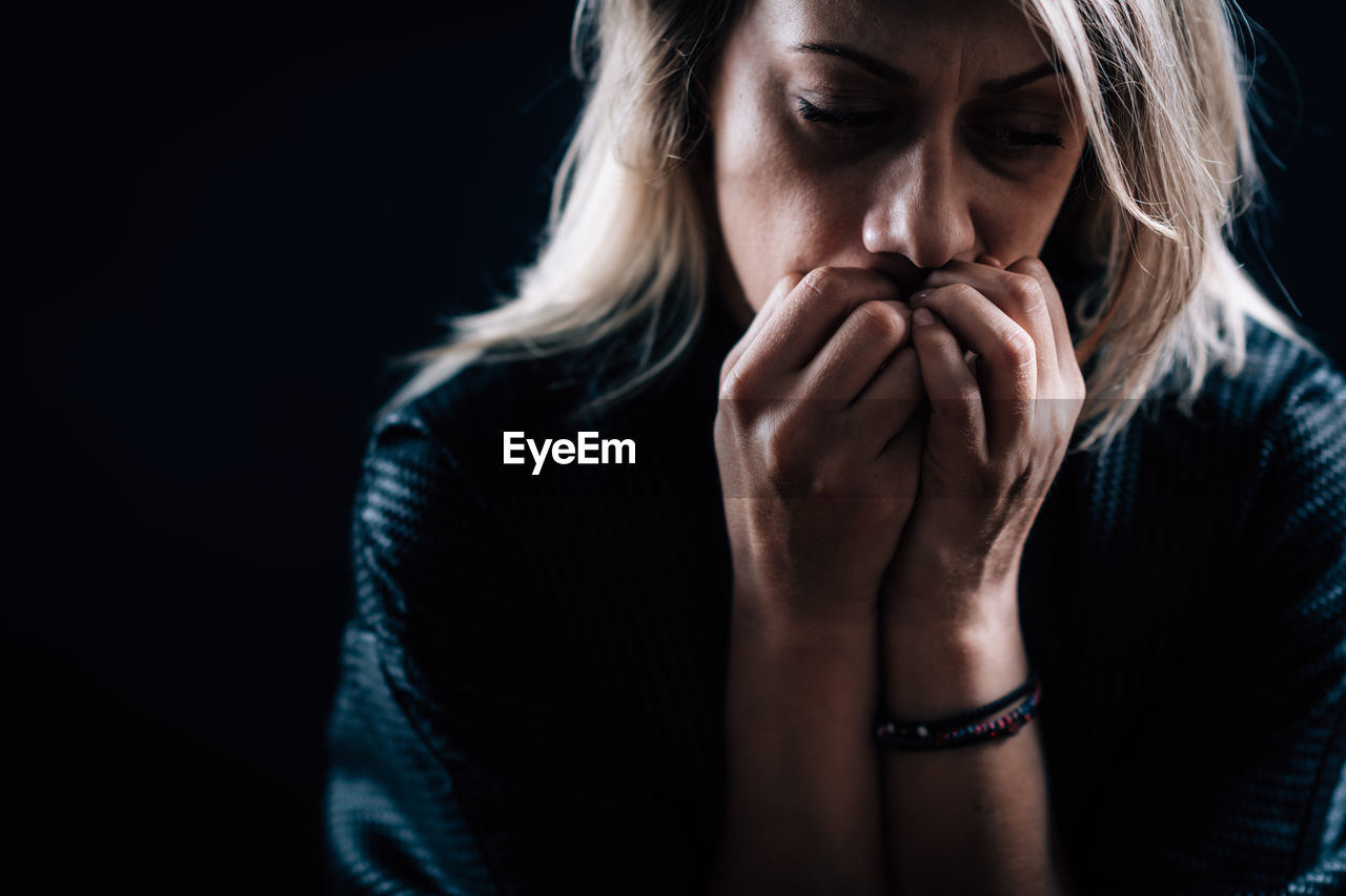 Close-up of depressed woman against black background