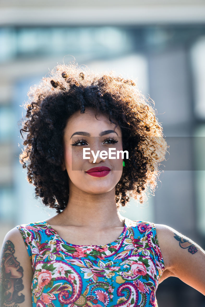 Fashionable young woman with curly hair in city