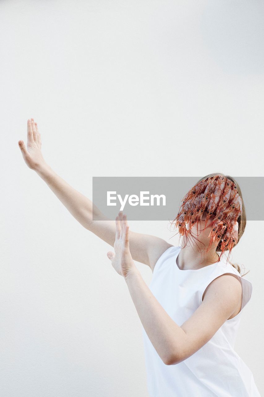 Teenage girl with shrimps on face standing against white background