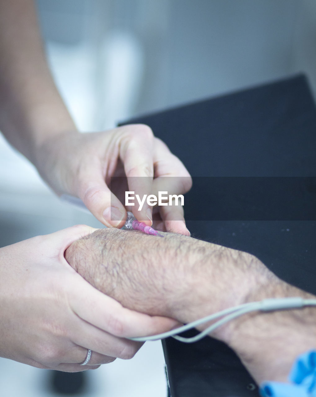 Cropped image of doctor injecting syringe on patient hand in hospital