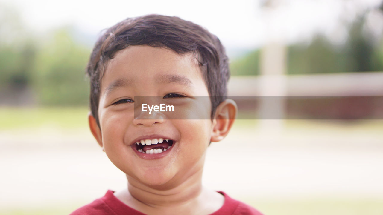 PORTRAIT OF BOY SMILING OUTDOORS