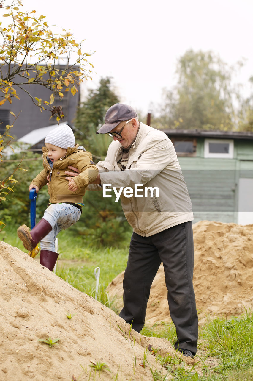 Grandfather assisting grandson in climbing rock