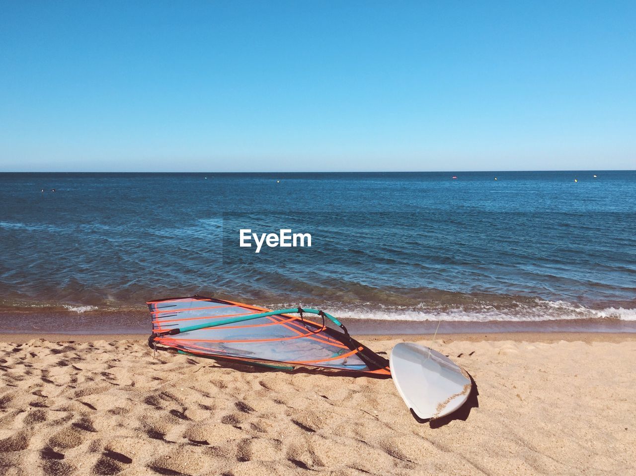 Abandoned windsurfing board on sunny beach